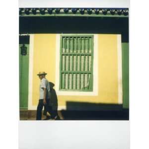  of Man Walking Past Yellow Wall with Painted Green Window Grille 